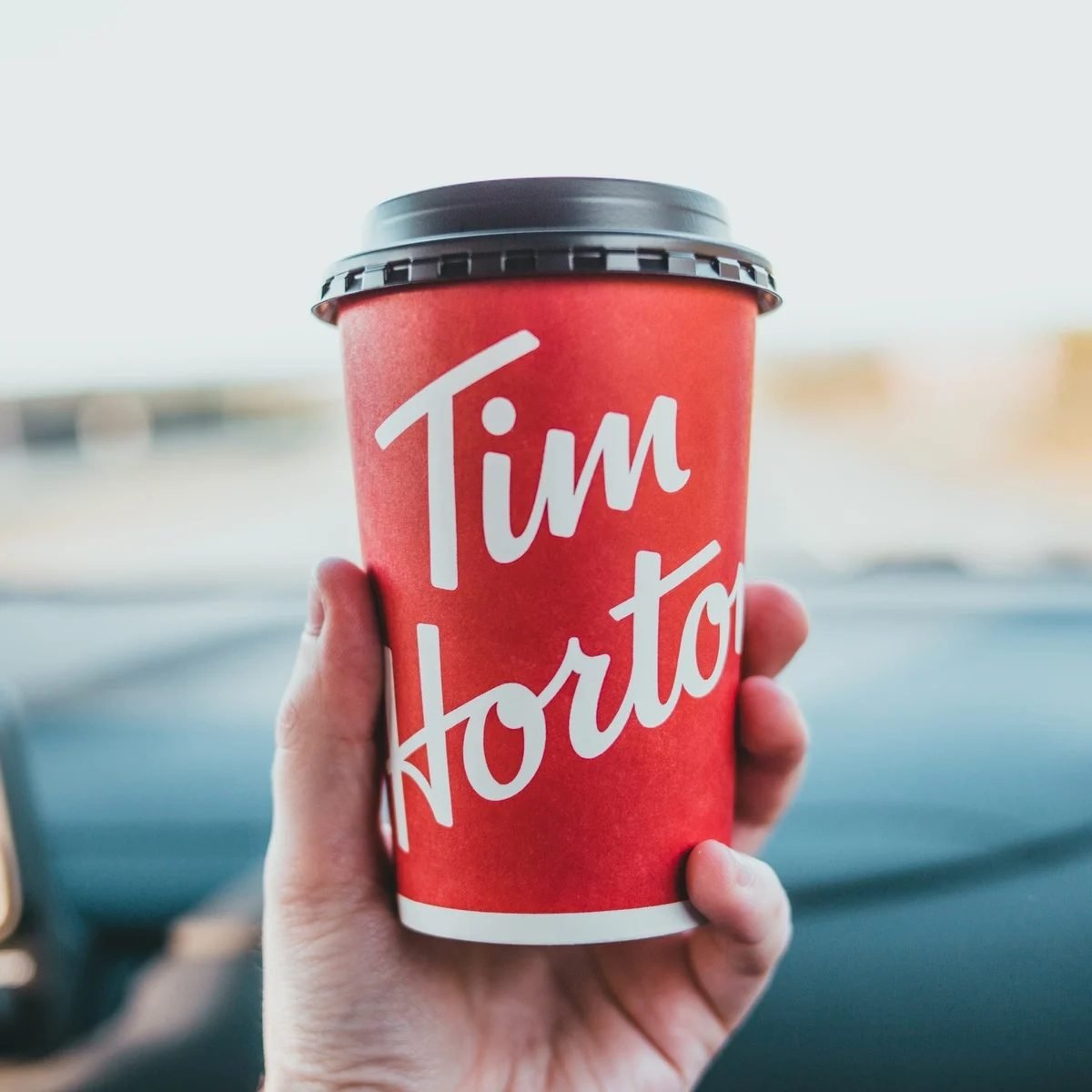 Photo of a hand holding the classic red Tim Hortons takeaway coffee cup